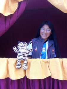 a girl stands in a theatre with a puppet