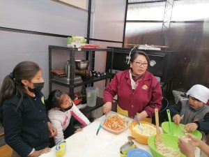 a woman and children are cooking in an industrial kitchen