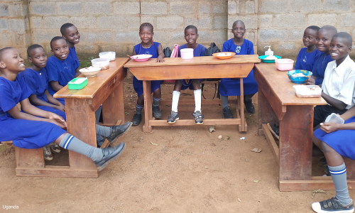 Group of children sitting at tables outside eating lunch