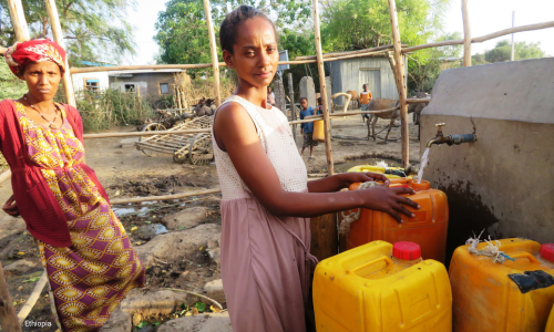 woman holding water canteen under a tap
