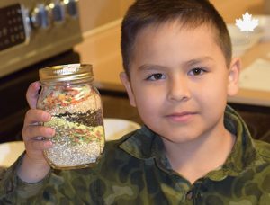 little boy holding a mason jar that has dried soup mix in it