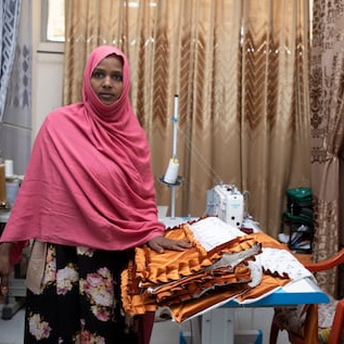 Kedija standing next to her sewing machine
